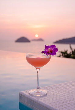 Cocktail rosa con fiore di ibisco su bordo piscina al tramonto sul mare