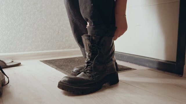 Careful fastening of boots in dawn light. Quietly securing combat boots at sunrise during daily routine. An intimate act of fastening sturdy combat footwear at daybreak in peaceful solitude