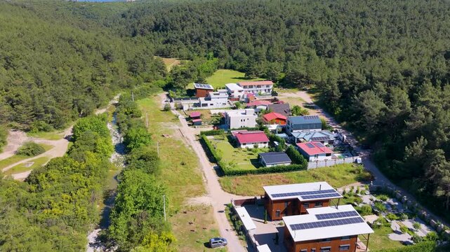 Aerial view of modern homes with solar panels nestled in a lush green forest