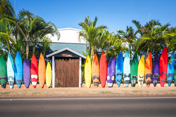 Colorful Surfboard Fence Lining a Tropical Street Beside Palm Trees and Blue Sky, Paia, Maui, Hawaii, USA © EyesTravelling