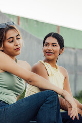 Fototapeta premium Dos jóvenes amigas latinas hablando y compartiendo un momento juntas al aire libre en el Día de la Juventud.