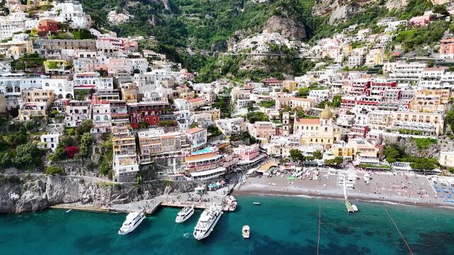 Aerial 4K video footage of Positano on the Amalfi Coast, Italy. Drone panorama of breathtaking cliffside townscape with colorful houses, Positano beach and Mediterranean sea views with ships
