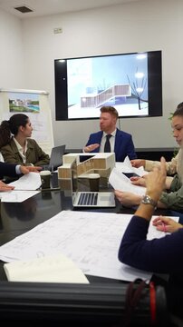 Business team of architects and engineers meeting in the office conference room to discuss a new building project with blueprints and model