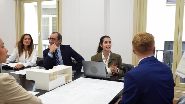 Business team of architects and investors meeting in a boardroom. Colleagues discussing a new building project using blueprints and a scale model