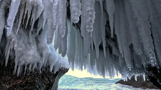 Ice stalactites formed inside a grotto within large coastal rocks after seawater spray freezing during winter conditions in the Black Sea
