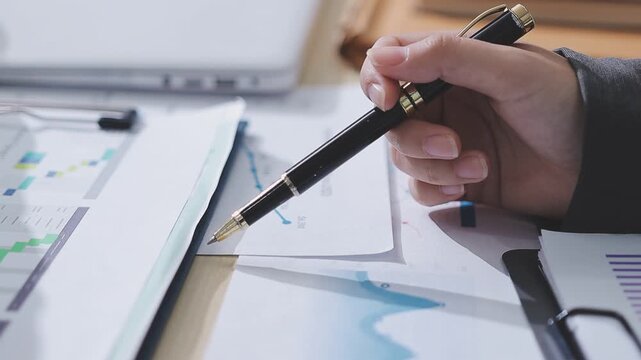 Two accountants examining financial documents using a calculator, taking notes, and discussing results, surrounded by documents and technology in a busy office environment. Audit and taxes in business