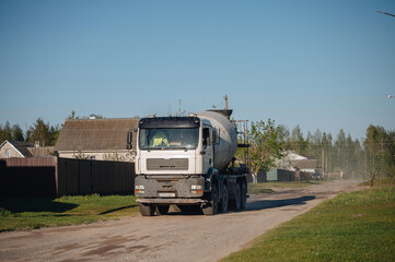 Obraz premium Heavy truck with a concrete cement mixer driving down the city street, construction and infrastructure concept
