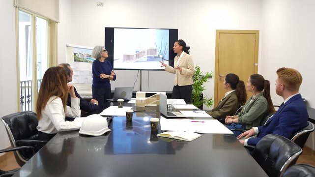 Young female architect presenting a new building design to her colleagues. Team of business people discussing plans in a modern office