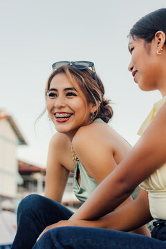 Primer plano de una joven latina sonriendo con brackets junto a su amiga en el D&iacute;a de la Juventud.