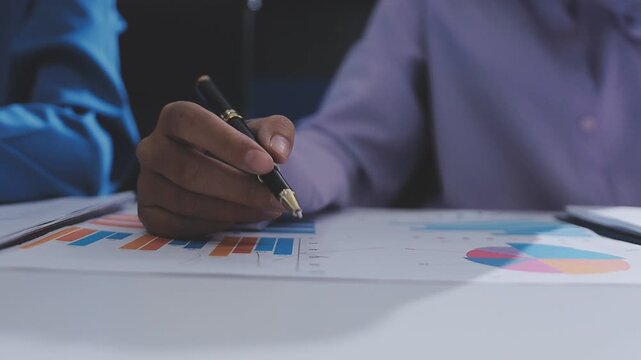 Two accountants examining financial documents using a calculator, taking notes, and discussing results, surrounded by documents and technology in a busy office environment. Audit and taxes in business