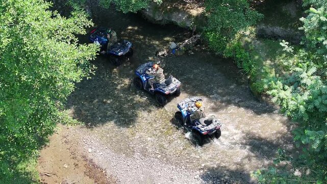 Aerial drone view of people riding quad bikes through a shallow river in a forest, Azerbaijan Drone, adventure outdoor activity