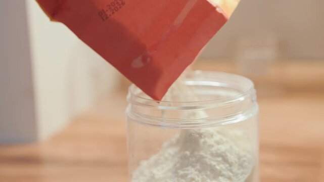Closeup flour pouring into jar during home baking lesson, student baker learning measurement and technique on wooden counter, warm natural light, tidy pantry jar in focus, recipe practice moment
