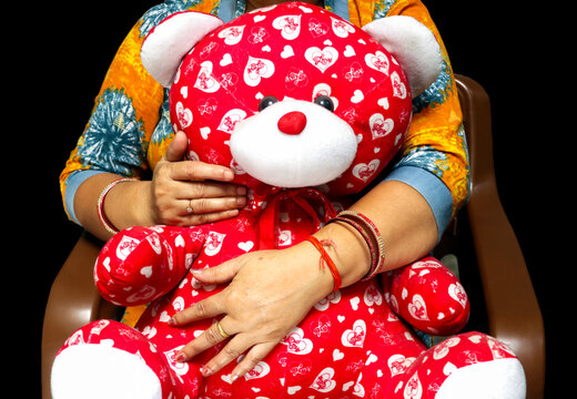 Woman Holding Red Teddy Bear with Heart Pattern Symbolizing Love