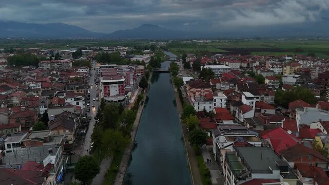 4K drone pull-away over the Black Drin River revealing riverside buildings in Struga, North Macedonia