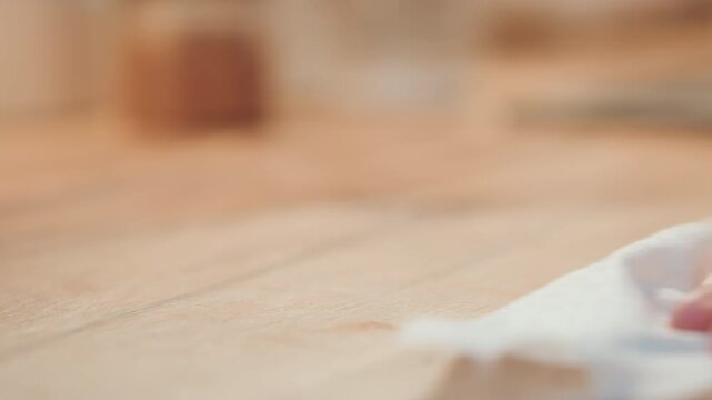 Wiping countertop after baking. Kitchen cleanup involving sugar debris and cloth polishing. Restoring tidy appearance by cleaning spilled sugar using circular motion and gentle pressure