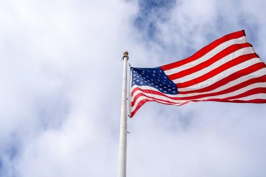 American flag waving on a tall pole against a cloudy sky