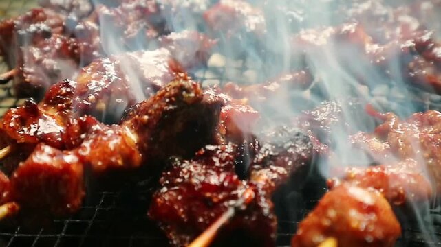 Close up shot of Indonesian beef satay grilling on charcoal grill with thick white smoke, delicious food.