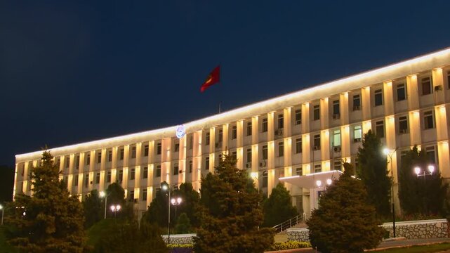 Osh, Kyrgyzstan - september 15th, 2025: Osh City Hall at night, Kyrgyzstan. Soviet Modernist architecture with illuminated facade and national flag central square. Historic administrative building.
