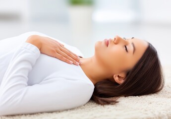 Obraz premium Peaceful young adult female with dark hair lies on a soft, light-colored carpet, eyes closed, hand resting on her chest