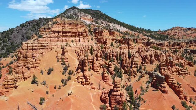 Cinematic drone footage flying over Dixie National Forest in Utah. Stunning aerial view of dramatic red rock spires, hoodoos, and geological formations similar to Bryce Canyon. 