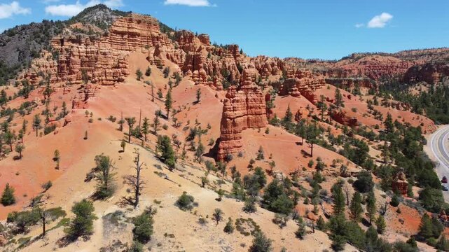 Cinematic drone footage flying over Dixie National Forest in Utah. Stunning aerial view of dramatic red rock spires, hoodoos, and geological formations similar to Bryce Canyon. 