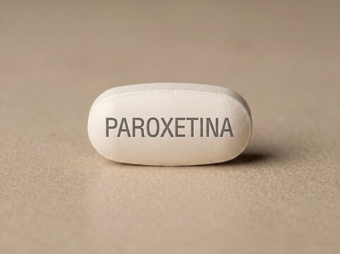 A professional photography close-up shot of an oblong white pill showing the name PAROXETINA printed on the front, displayed on a minimalist neutral background.