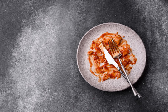 A dirty plate after a meal with leftover pasta and tomato sauce, cleaning. An empty dirty plate