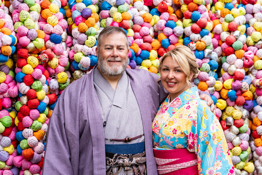 Man and woman dressed in a kimono looks at Kukurizaru color ball ema at Yasaka Koshin-do temple, Higashiyama District, Kyoto Japan