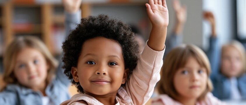 A bright young girl eagerly raises her hand in a classroom setting, representing curiosity, engagement, and the importance of education in a supportive learning environment.