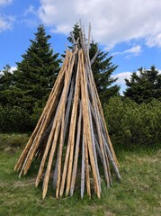 Traditional wooden log teepee structure on a mountain hiking trail © Konrad_elx
