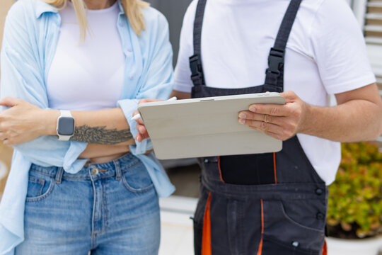 Contractor and client reviewing a job estimate on a digital tablet, discussing home maintenance services and service interaction during an outdoor consultation