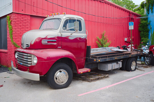Vintage Ford Truck F5,Red Flatbed Truck Parked Beside a Bright Red Industrial Building Editorial Use Only St. Petersburg, FL USA May 30, 2026 evoking nostalgia with worn chrome details, rustic texture
