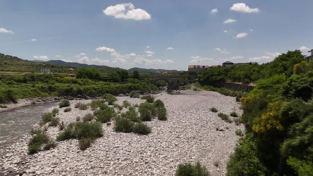 4K drone low flight tracking forward and flying underneath the historic Ottoman Mesi Bridge in Shkoder, Albania