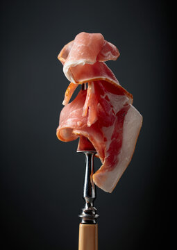 Raw fresh smoked pork bacon slices on a fork.