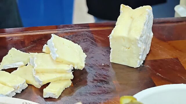 Chef cutting camembert brie cheese into slices with knife, Dairy Product Preparation, Professional Kitchen Work, Deli Restaurant Serving