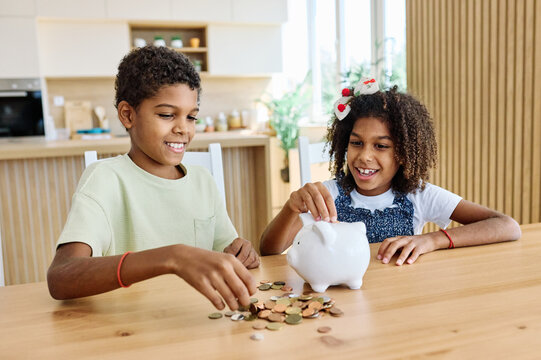 Family brother and sister, girl and boy, putting coin money in piggybank at home. Personal savings, Bank safety and financial investments concept
