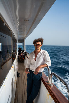 Epic luxury yacht cruise man portrait vertical linen shirt lifestyle ocean background.
