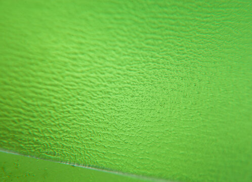 Green textured surface with visible patterns and details under close-up view in a bright setting