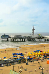Obraz premium Scheveningen Pier with bungee jumping tower, beach umbrellas and the North Sea coast.