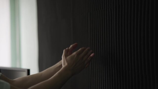 Close-up of sound engineer clapping hands to test acoustic absorption of new soundproofing foam panels, evaluating the room echo and reverberation for audio quality improvement, closeup, slow motion.