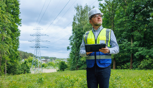 Energy engineer, auditor inspecting power lines in spring forest. Power grid maintenance and inspection. Ecologist assessing infrastructure impact on spring forest nature. Climate change.