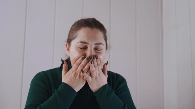 Caucasian woman clutching chest at home, gasping and covering mouth, anxious expression, panelled interior, tentative breathing, reaching for phone, emotional distress suggesting medical emergency,