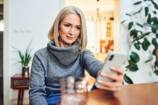 Woman using smartphone at home dining table