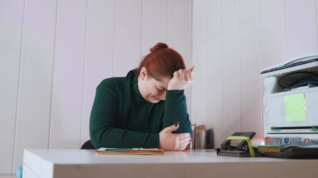 Office employee appears exhausted while manager recuperates in disorderly surroundings. Fatigued office personnel find moments of rest amid messy workspace with supervisor recovering nearby