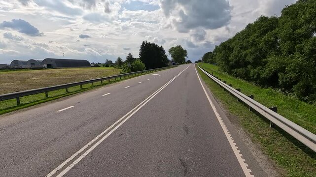 The car drives along the road on a summer day. Highways, roadside and road line markings.