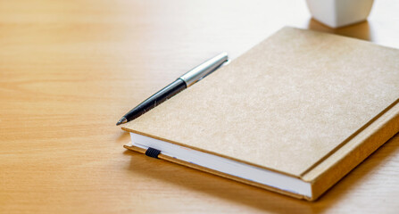 Simple brown notebook and pen on wood