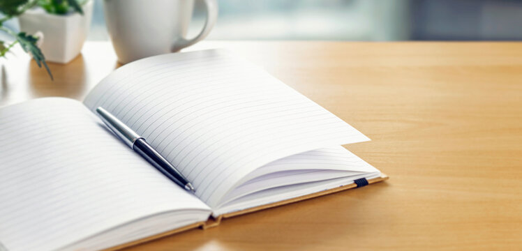 Open blank notebook with pen on desk