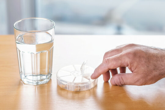 Male hand reaching for daily medicine organizer