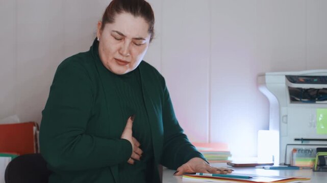 White woman writing documents at desk then pausing with hand to chest, client noting symptoms and worrying over paperwork, calm interior lighting, visible files and printer, anxious expression