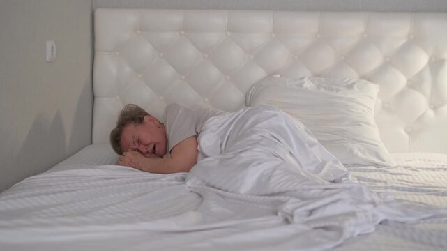 An elderly woman is crying while lying in bed